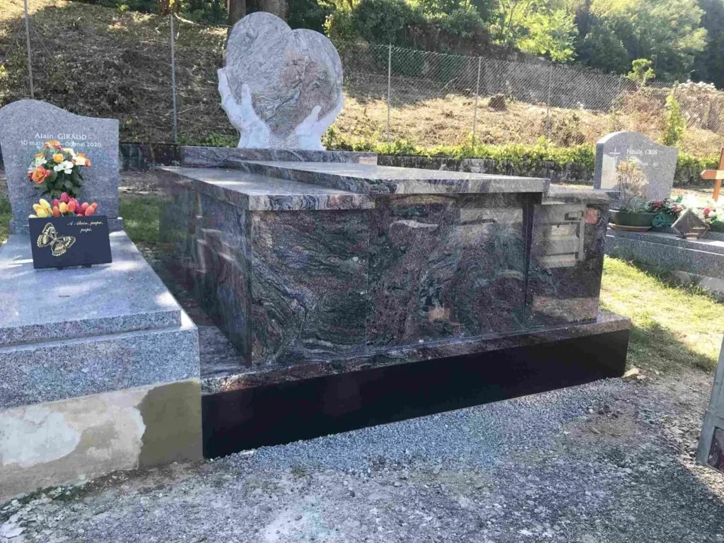 Monument funéraire sculpté en granit aux motifs veinés avec stèle en forme de cœur.