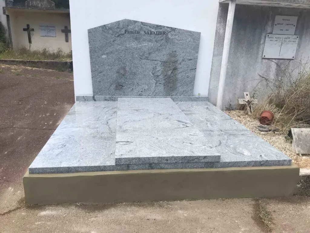 Sépulture sobre en granit gris clair avec stèle épurée au cimetière.