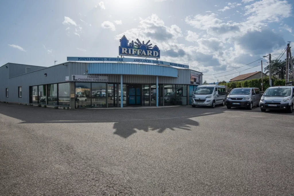 Façade des pompes funèbres Riffard avec parking et véhicules de service.
