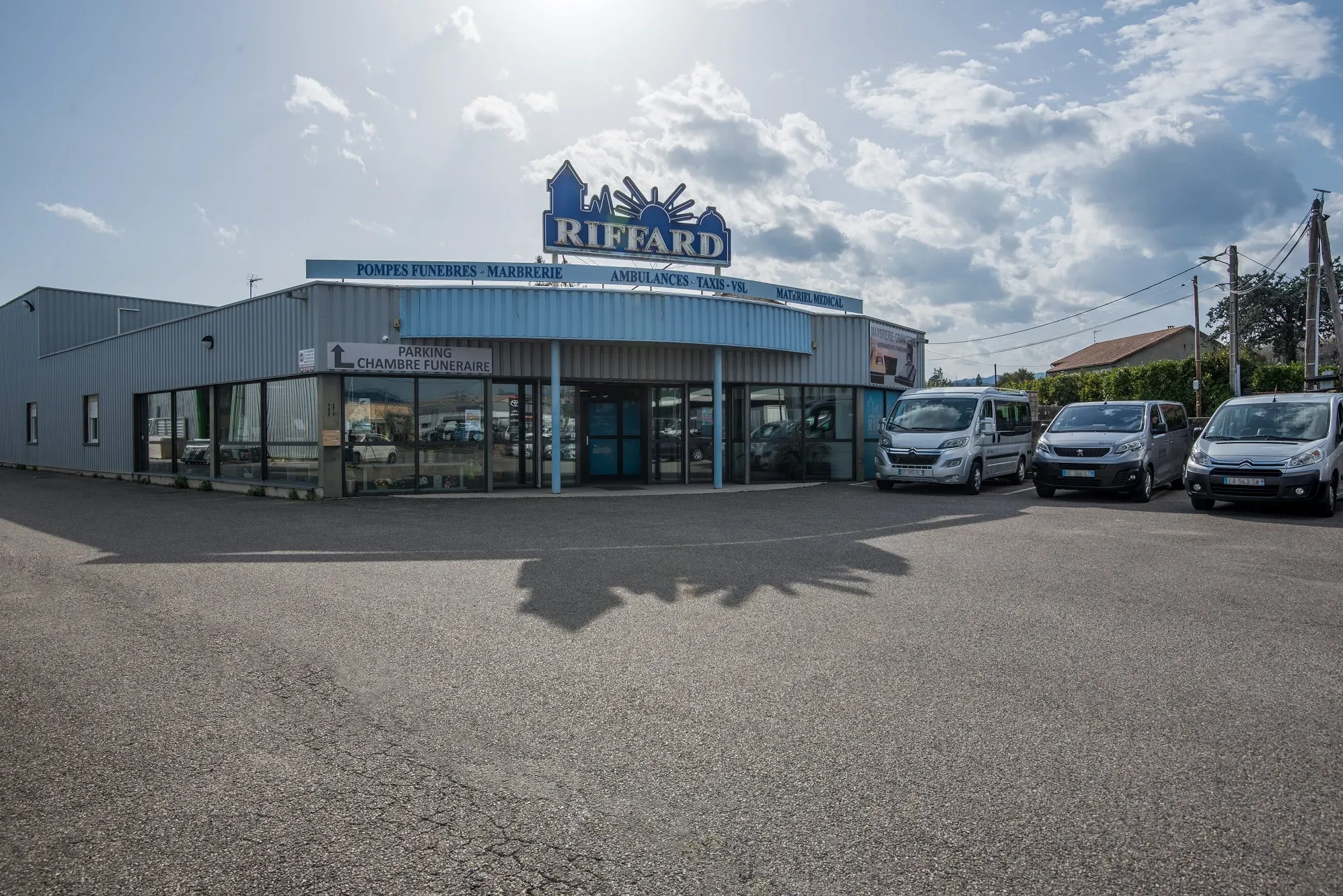 Façade des pompes funèbres Riffard avec parking et véhicules de service.