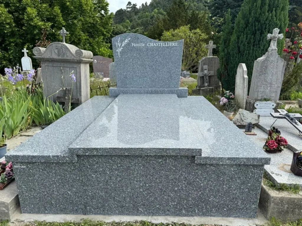 Monument funéraire imposant en granit gris poli posé dans un cimetière.