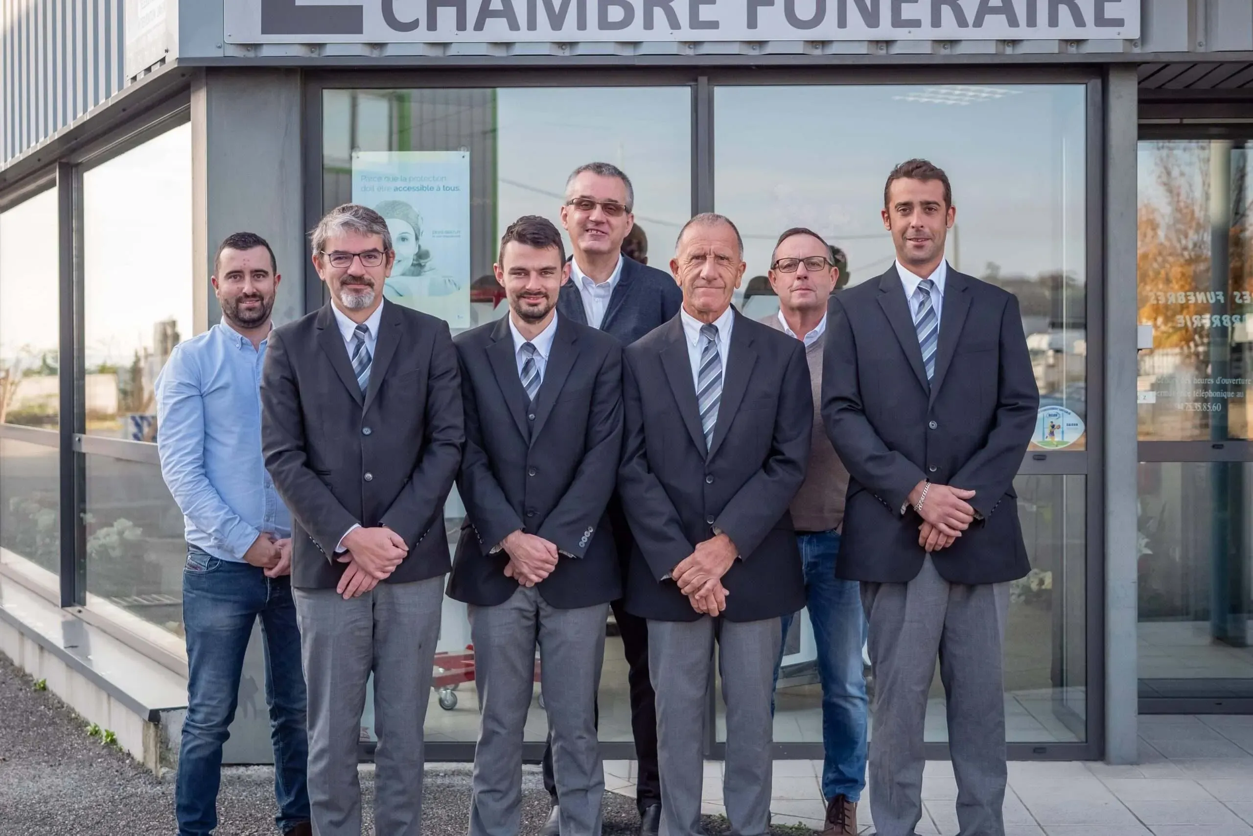 Équipe des pompes funèbres pose devant l'entrée de la chambre funéraire.
