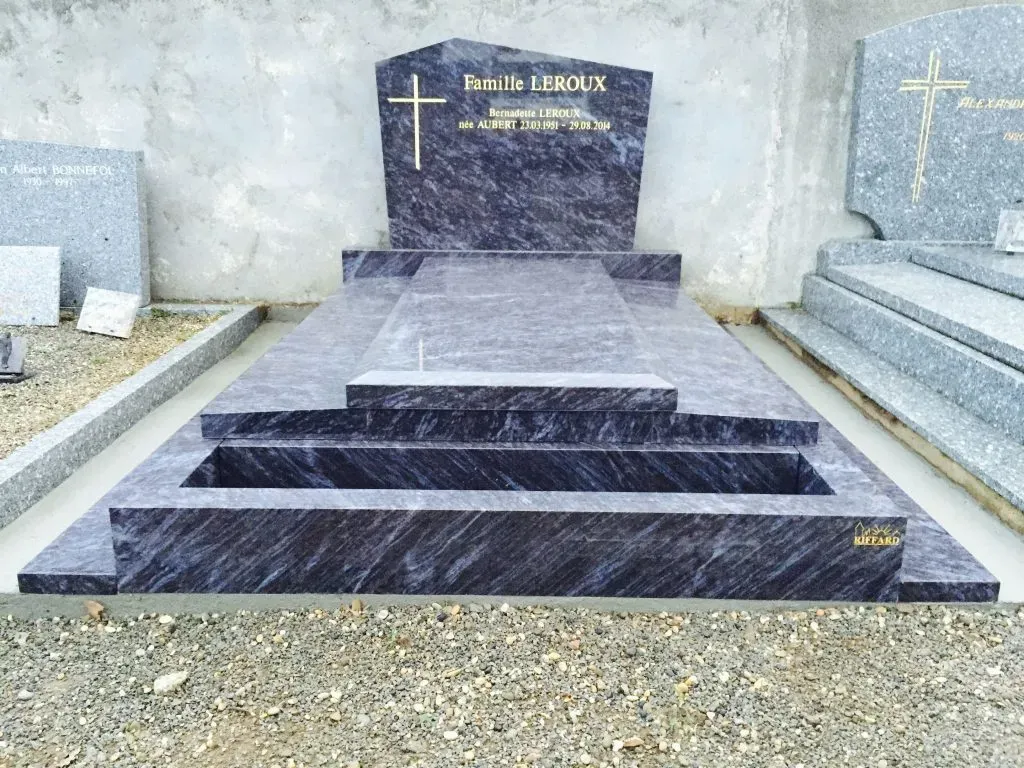 Sépulture moderne en granit bleu avec stèle inclinée et gravures dorées.